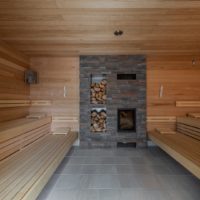 Thermalbad Aukammtal Wiesbaden: Feuersauna mit Kamin aus Naturstein und Holzlager