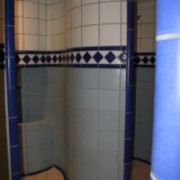 Wandverblendung einer runden Wand mit radialer Keramik als Kandbelag mit keramikmosaik Keramikband an Lampierie. Ornmentband in Dusche im Spa einer Wellnessanlage.