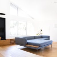 Moderner Gaskamin in der Wand. Schwarz Anthrazit mit Holz-Design im Wohnzimmer unter der Dachschräge.