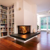 Moderner Kachelkamin im modernen Design mit anthrazit Schiefer, verputzt, in der Ecke des Wohnzimmers.