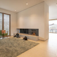 Gaskamin als Raumtrenner zwischen Woihnzimmer und Esszimmer. Moderner Kamin mit gefliester Rückwand als Designkamin.