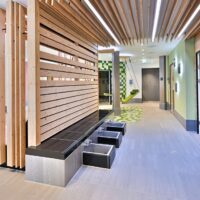 Auf der Wärmebank mit Fußbädern bereitet man sich für den Saunagang vor – die Kräutersauna direkt vor Augen.
